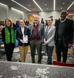 Faculty standing for a photo in an auditorium