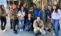 a group of students stand for a photo by a statue