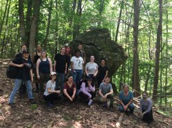 MSU archaeological field school students and staff in front of a large stone feature