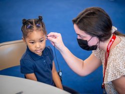 An audiology student administers a hearing test to a young child