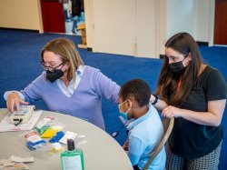 Professor Maryrose McInerney assists audiology student Alyssa Bonapace, in conducting a otoacoustic emission test on a young student in Newark.