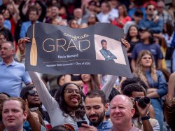 in a large crowd, Kiana Bernard celebrates her brother, Kevin with a large sign