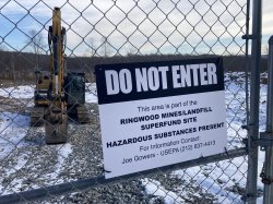 photo of Do Not Enter sign on fence. Behind the fence, a large piece of construction equipment sits, covered in snow