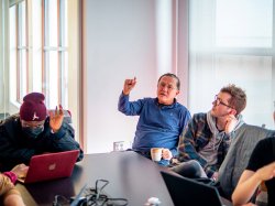 "A professor gestures while speaking to a group of students."