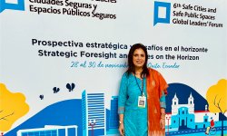 photo of Professor Sheetal Ranjan standing in front of a banner wall for conference in Ecuador