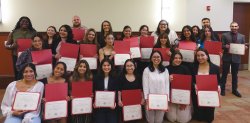 a group of students pose while holding certificates in red folders