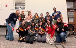 a group of people pose for a photo, each waving a small German flag