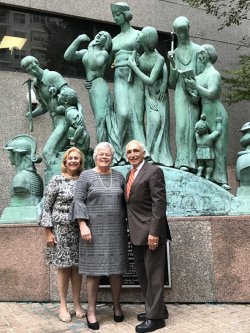 three people standing in front of statue