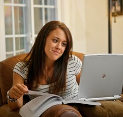 student studying with book and laptop on chair