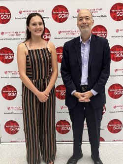 A student and her mentor standing in front of a university branded backdrop