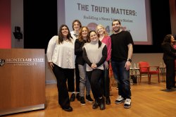 A team of six students in a group standing on a stage.