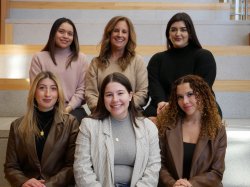 A team of six students and faculty sitting in two rows, smiling and dressed professionally.