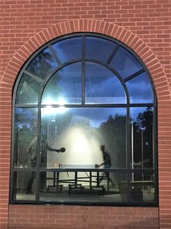 View through window of two people playing table tennis