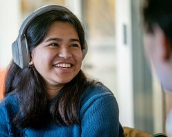 student wearing headphones smiling talking to friends