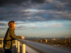 Student gazing out at view of manhattan skyline from campus building.