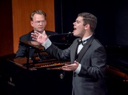 Male student singing at recital with pianist accompaniment