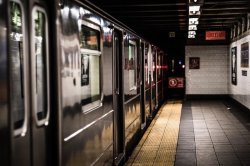photo taken from subway platform with a subway car at the station. doors are closed and platform is empty. image by Adi Goldstein, courtesy of Unsplash.