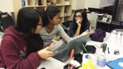 Girls discussing project with open laptop computer