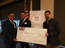 Two students and professor hold oversized prize check.