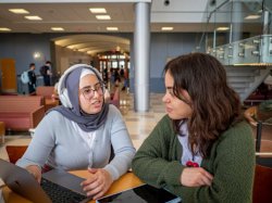 Two students conversing about a project at a table in the lobby of the center for environmental and life sciences