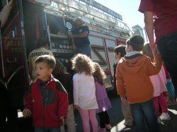 Little Falls Fire Department firefighters show children one of their fire trucks.