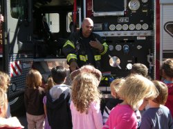 Little Falls firefighter shows children personal protective gear.