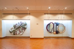 Two large artworks in separate glass cases in the lobby of the Kasser Theater.