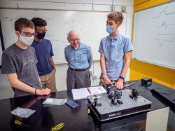 Weston with three students showing him their experiment using lasers and prisms