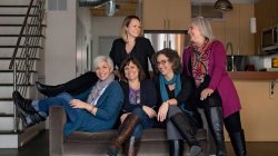 five women seated on a couch in a high-end loft apartment