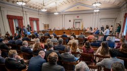 Crowd of people sitting down and listening to government officials speak