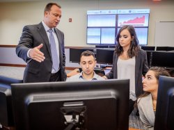 Teacher and students looking at a computer in the School of Business