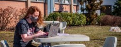 photo of Student on laptop outside in mask
