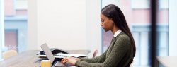 woman Working On Laptop At Desk In Meeting Room