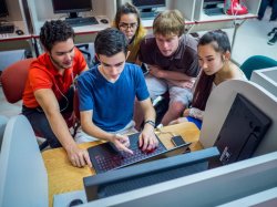 diverse group of five students working together around a laptop computer