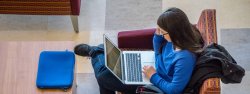 overhead photo of female student in lounge chair working on laptop