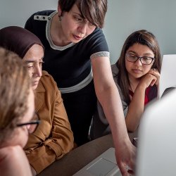 Female professor pointing out something on a laptop screen