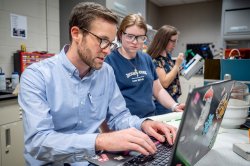 Person typing on computer while a student watches.