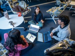 Three students sitting in a circle apart of a discussion.