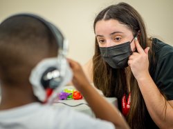 Student pointing at ear with an adolecent.