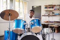 Male Teenage Pupil Playing Drums In Music