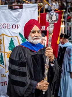 Harbans Singh holding the university mace and leading the commencement processional