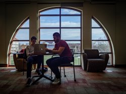 two students studying inside near a window