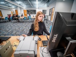 student using microfilm reader in library