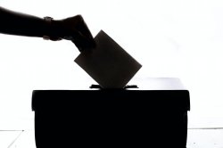 silhouette of hand placing vote in ballot box