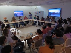 students sitting in a circle of desks in a darkened classroom