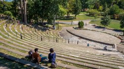 Photo of the campus amphitheater in spring or summer with two students sitting on the steps.
