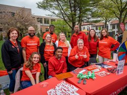 Montclair Alumni gathered around a table wearing matching red "One Day for Montclair" t-shirts