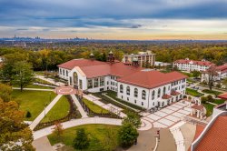 aerial photo of College Hall with NYC skyline in background at dusk