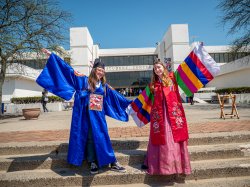 Photo two students dressed in traditional Korean costume on campus