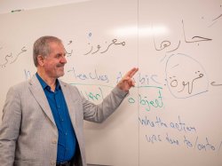 photo of Professor Mazooz Sehwail pointing to a white board with Arabic writing